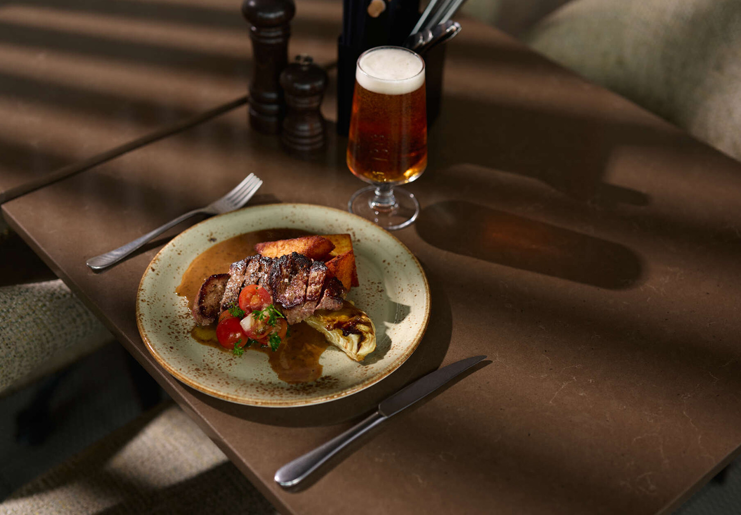 Ryggbiff med pepparsås och potatis serverad på restaurangbord.